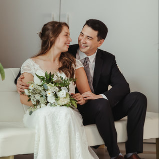 woman and man in wedding attire sit on couch 